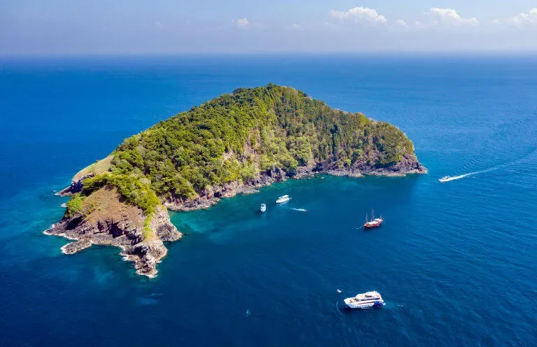 Île tropicale verdoyante entourée d'une mer bleue avec des bateaux