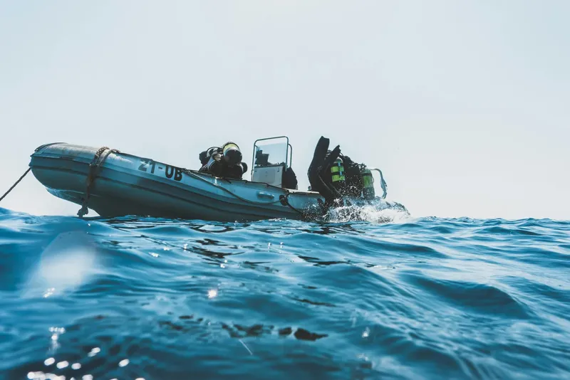 Plongeurs se préparant à entrer dans l'eau depuis un bateau semi-rigide