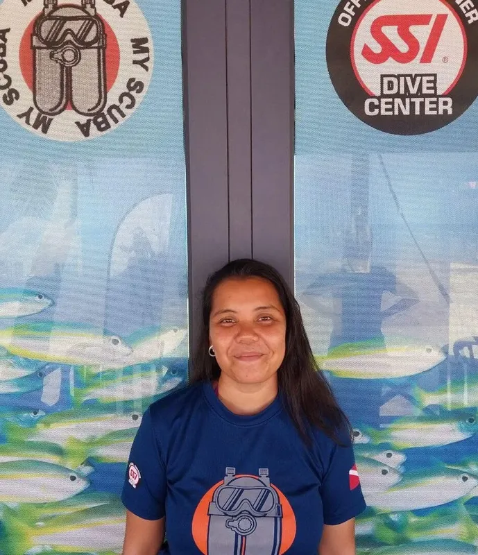 Femme souriante devant un décor marin et des logos de plongée