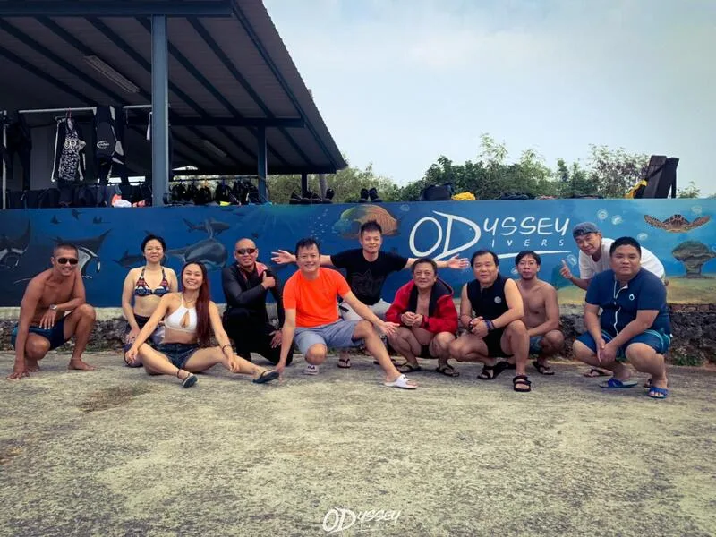 Groupe de personnes souriantes posant devant un mur décoré de fonds marins