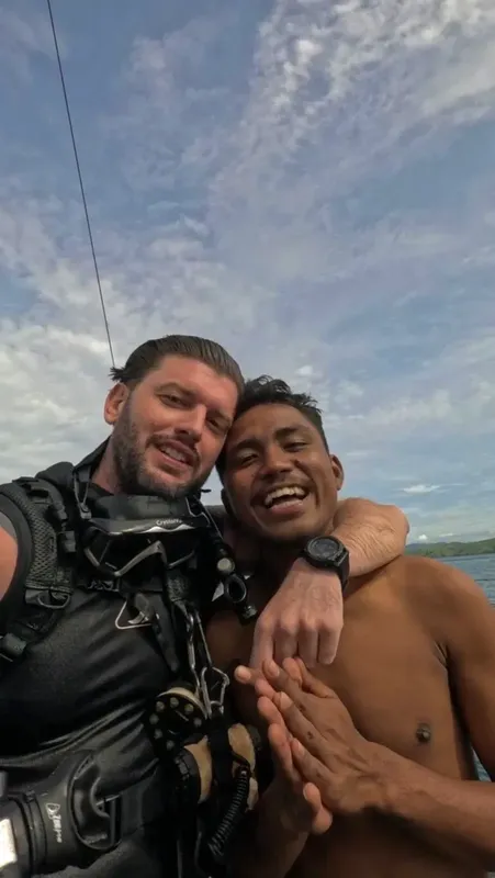 Deux hommes souriants, équipés pour la plongée, se prennent en photo