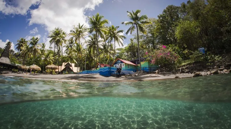 Plage tropicale avec bâtiments colorés et eau turquoise claire