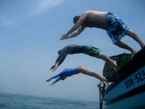 Trois personnes sautent d'un bateau en mer, activité estivale