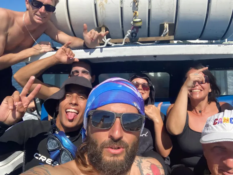 Groupe de personnes souriantes sur un bateau de plongée ensoleillé