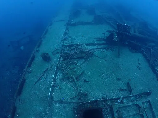 Épave de bateau coulé, structure métallique rouillée, fond marin bleu