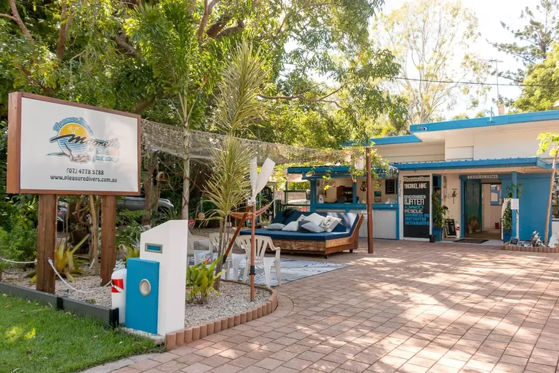 Devanture d'un centre de plongée avec enseigne, mobilier extérieur et végétation tropicale