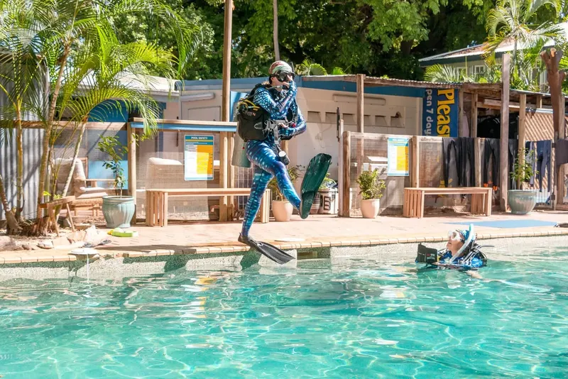 Deux plongeurs s'entraînent dans une piscine, un saute et l'autre flotte