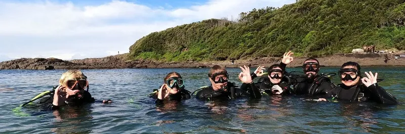 Groupe de plongeurs souriants dans l'eau, avec équipement sur le dos