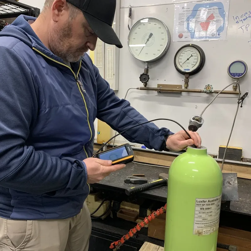Un technicien vérifie une bouteille de plongée avec un appareil numérique
