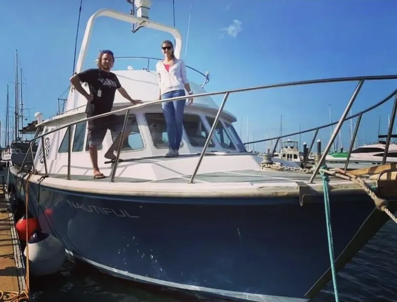Deux personnes souriantes se tiennent debout sur un bateau amarré