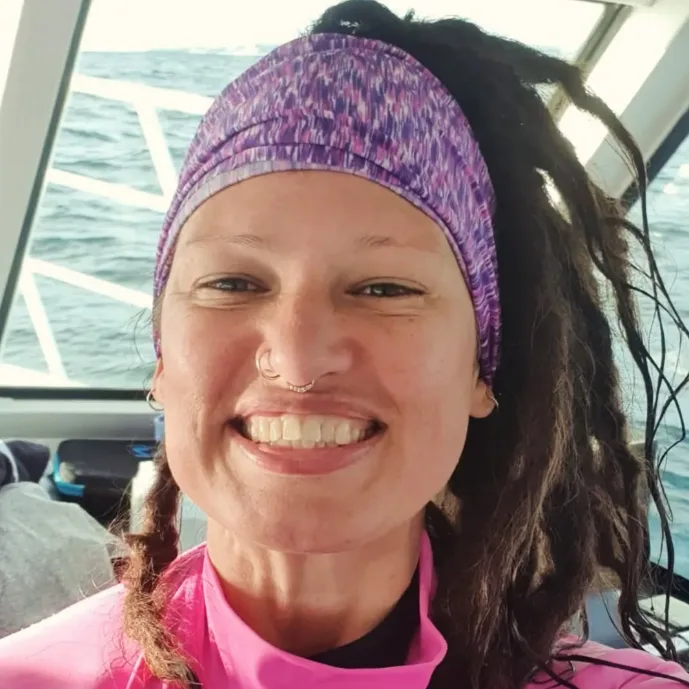 Femme souriante avec bandeau violet et cheveux tressés en mer