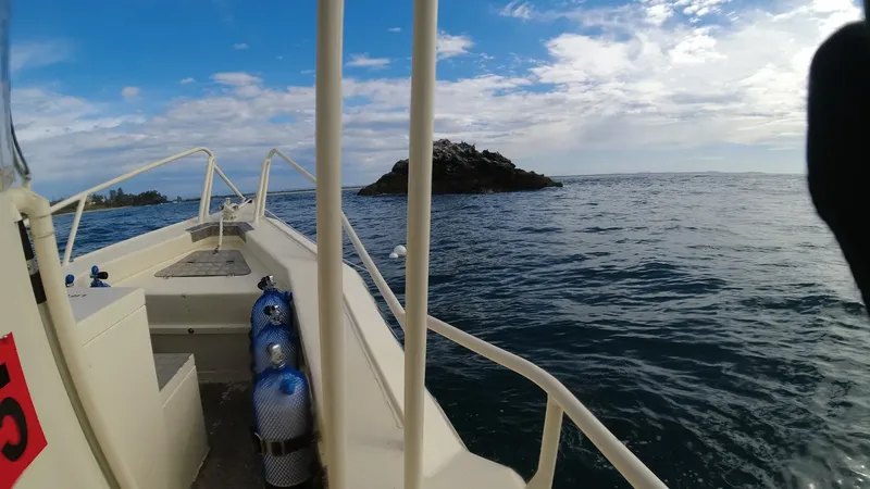 Bateau de plongée en mer avec des bouteilles et un îlot rocheux