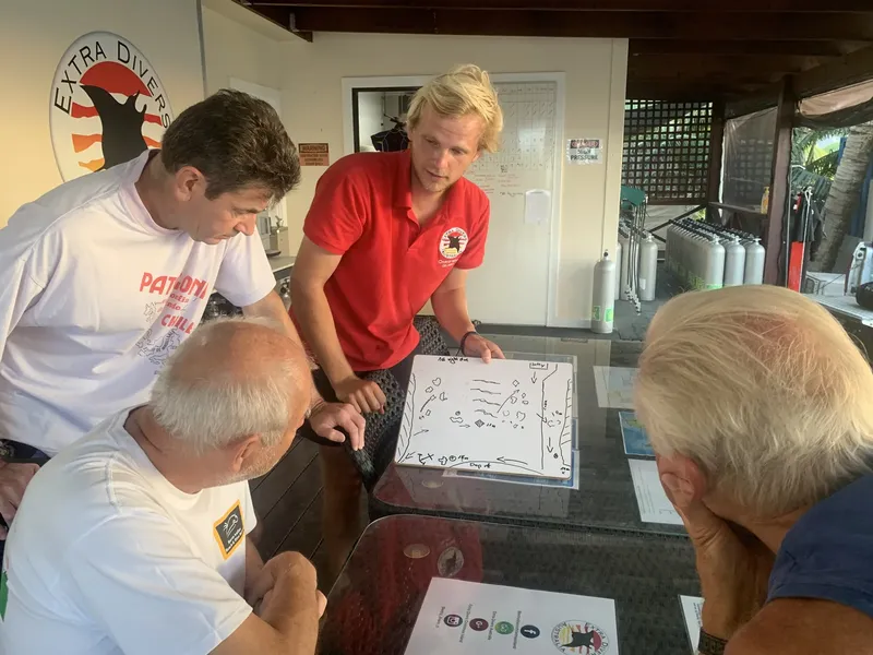 Groupe de plongeurs discutant d'un plan de plongée sur une carte