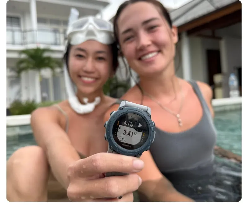 Deux femmes souriantes montrent une montre de plongée Garmin