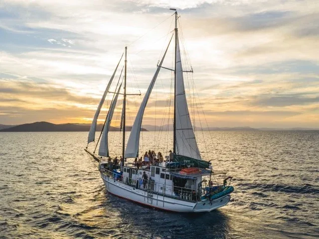 Grand voilier en mer avec des passagers au coucher du soleil