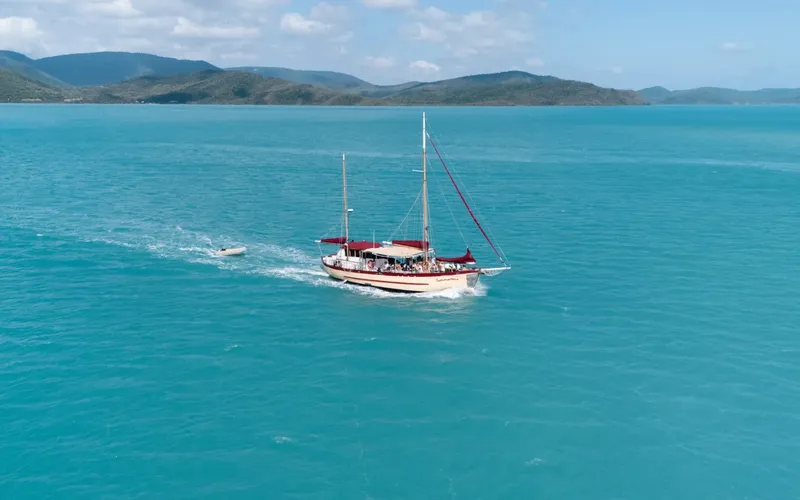 Voilier en mer avec des passagers, paysage côtier en arrière-plan