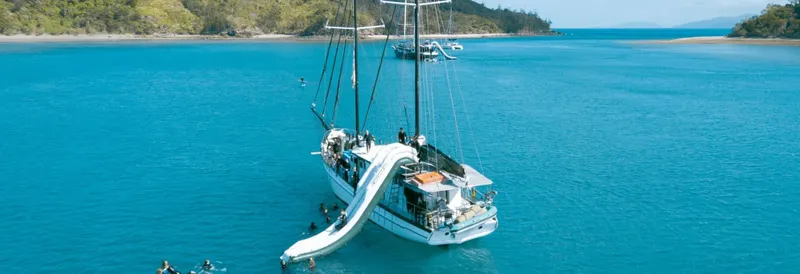 Catamaran amarré dans une eau turquoise avec des personnes à bord