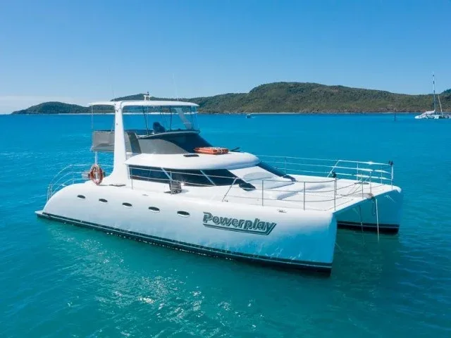 Catamaran blanc sur mer turquoise, avec le nom Powerplay visible