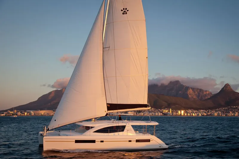 Catamaran blanc naviguant sur l'océan avec des montagnes en arrière-plan