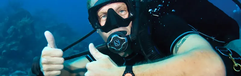 Plongeur souriant avec signe de validation sous l'eau bleu profond