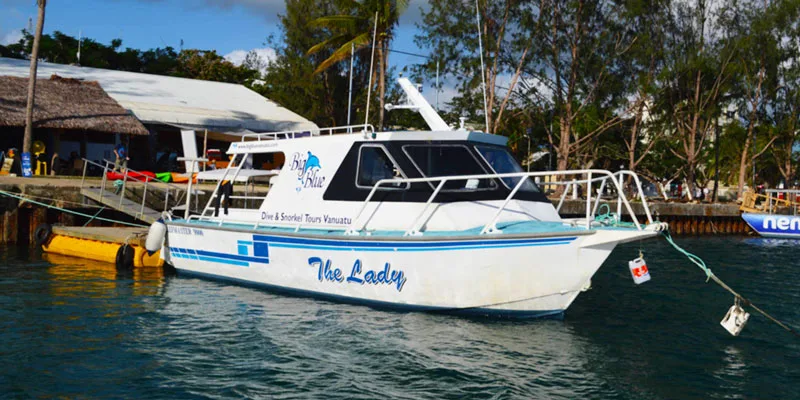 Bateau de plongée amarré à un quai avec des personnes à proximité