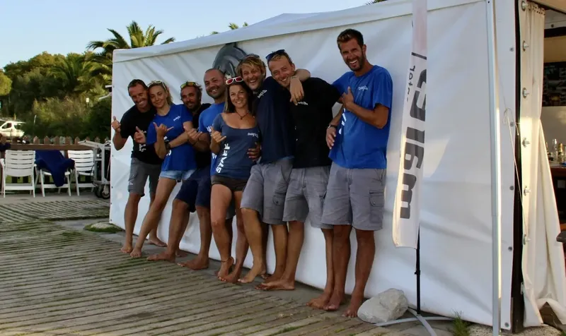 Groupe de personnes souriantes faisant des signes positifs devant une tente
