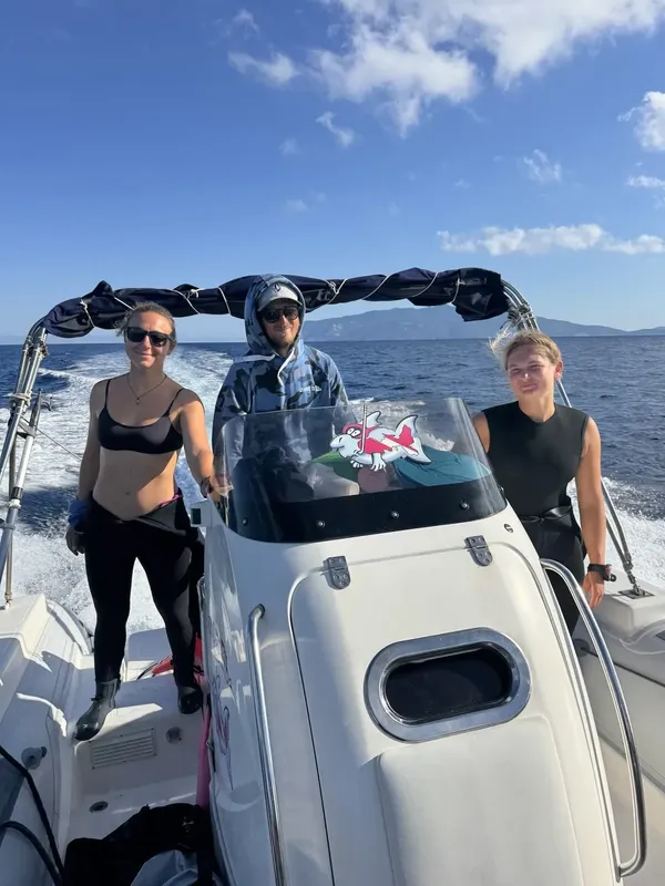 Trois personnes sourient à bord d'un bateau rapide en mer