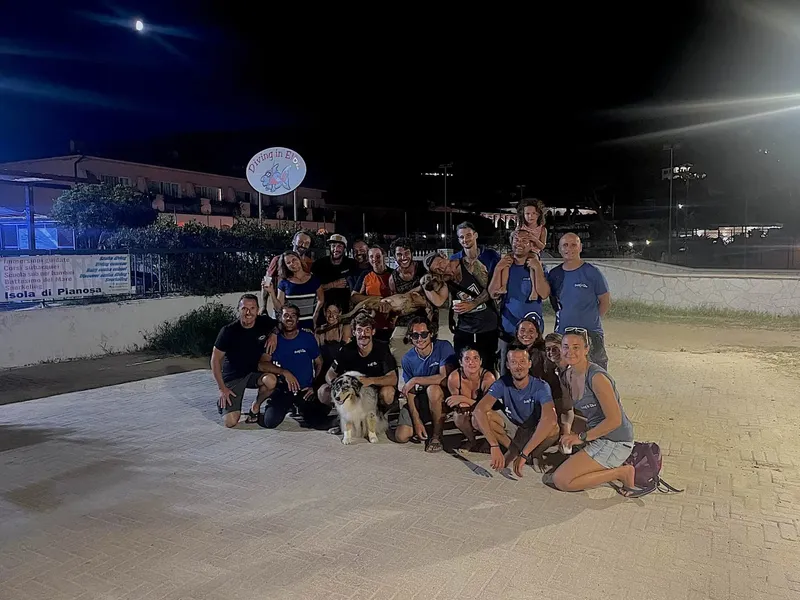 Groupe de plongeurs souriants posant devant le centre avec un chien