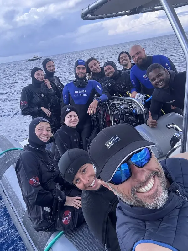 Groupe de plongeurs souriants à bord d'un bateau pneumatique bleu