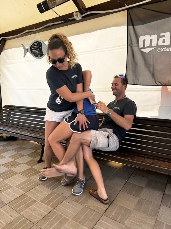 Deux personnes s'entraident à enfiler une combinaison de plongée