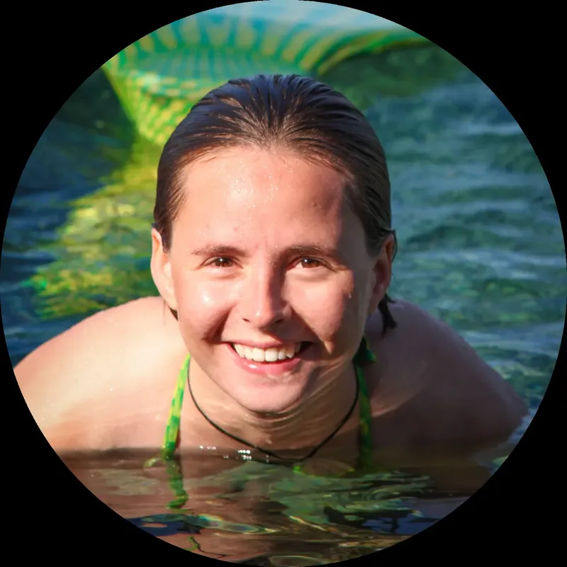Femme souriante dans l'eau avec une queue de sirène colorée