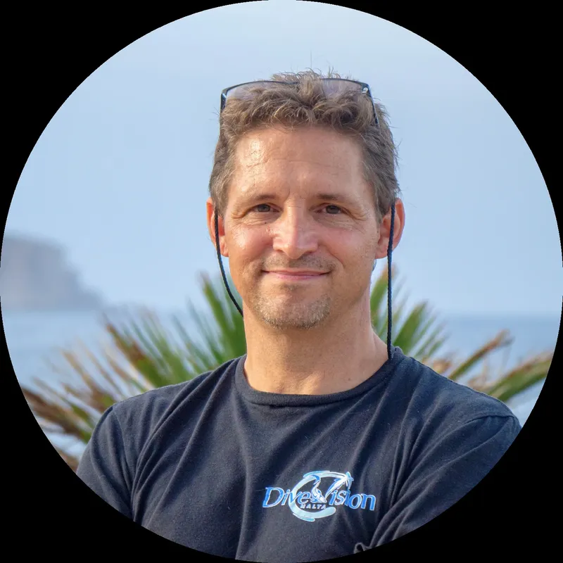 Portrait d'un homme souriant avec un t-shirt bleu et des lunettes