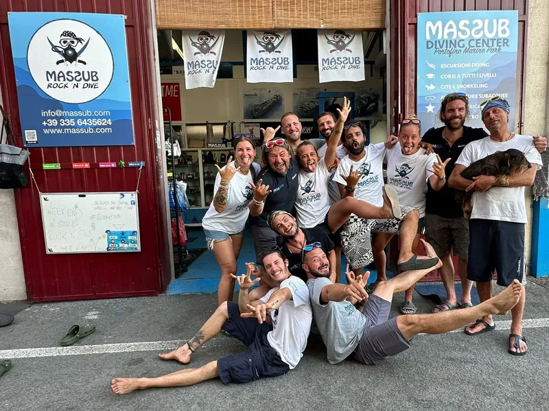 Groupe de plongeurs souriants devant la devanture d'un centre de plongée