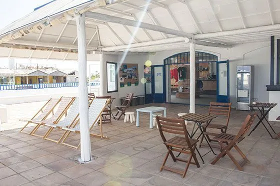 Terrasse ombragée avec mobilier de jardin et entrée d'un commerce