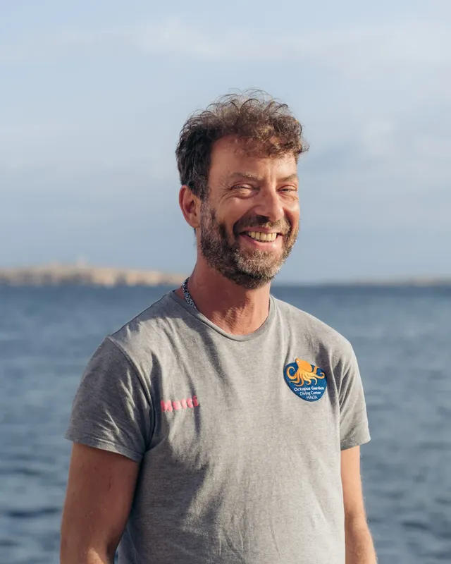 Homme souriant, portant un t-shirt bleu avec un logo coloré