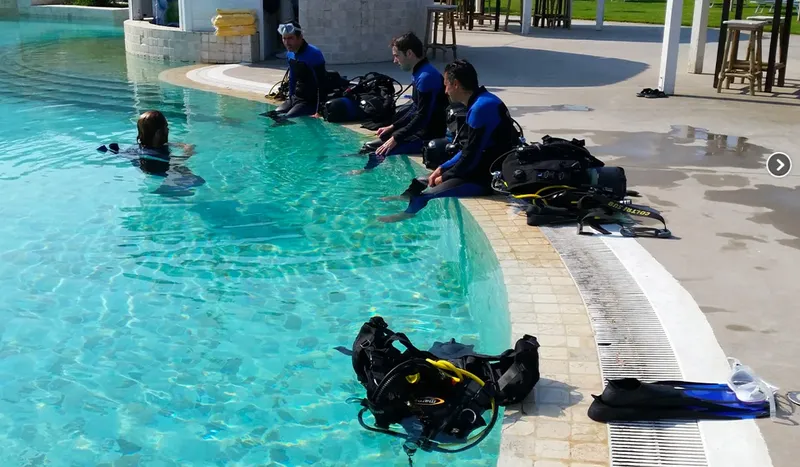 Des plongeurs en combinaison s'entraînent dans une piscine avec leur équipement