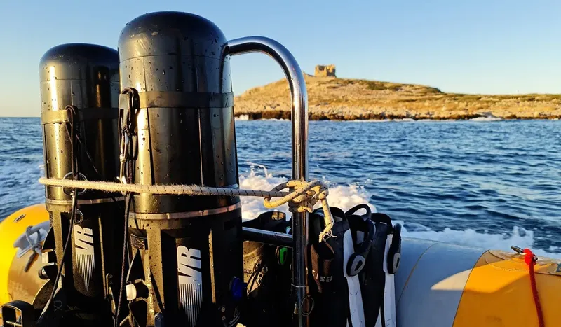 Bateau semi-rigide jaune naviguant en mer vers une île rocheuse