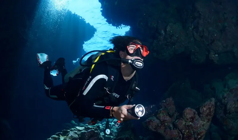 Plongeur avec lampe torche explore une grotte sous-marine éclairée