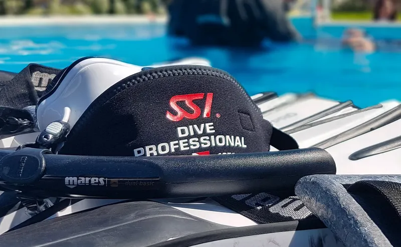 Equipement de plongée avec logo SSI et palmes noires près d'une piscine