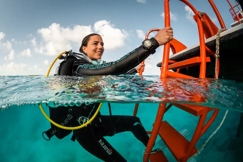 Plongeuse souriante sortant de l'eau à l'aide d'une échelle orange