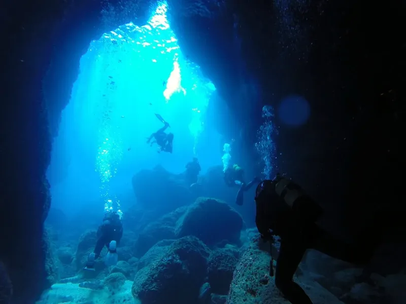 Plongeurs explorent une grotte sous-marine avec lumière filtrant en surface