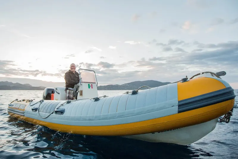 Homme conduisant un bateau semi-rigide jaune et blanc sur la mer