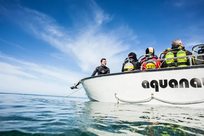 Plongeurs à bord d'un bateau blanc sur une mer calme