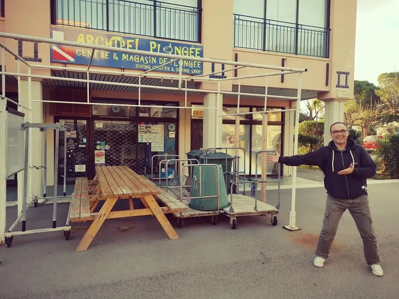 Devanture d'un centre de plongée avec une personne souriante et du matériel
