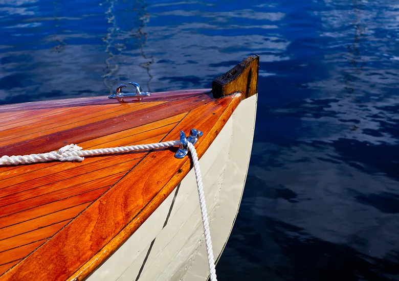 Proue d'un bateau en bois flottant sur une eau bleue calme