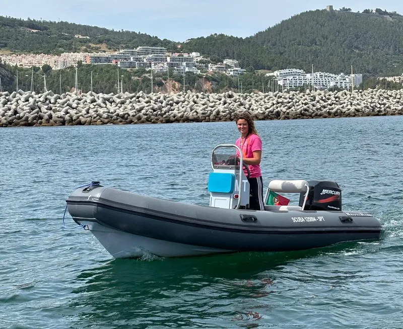 Femme conduisant un semi-rigide noir sur une mer calme et bleue