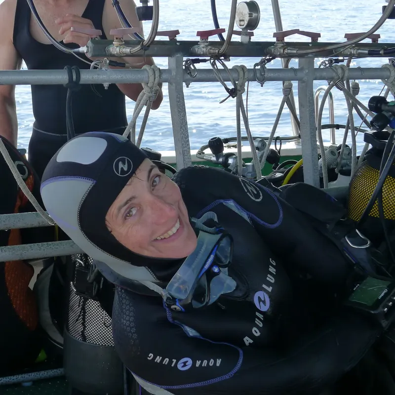 Plongeuse souriante sur un bateau avec son équipement complet