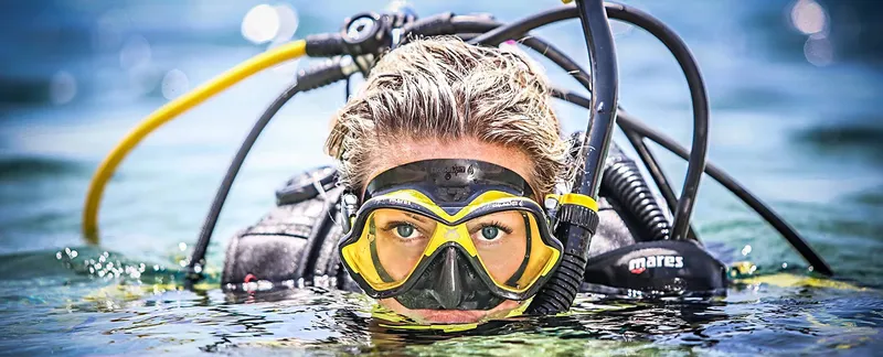 Plongeuse souriante avec masque et équipement complet sous l'eau