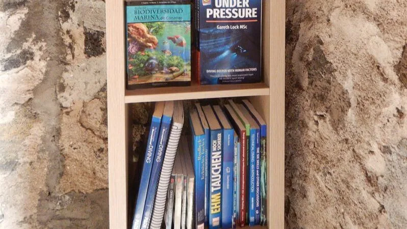 Bibliothèque blanche remplie de livres sur la plongée et la faune marine