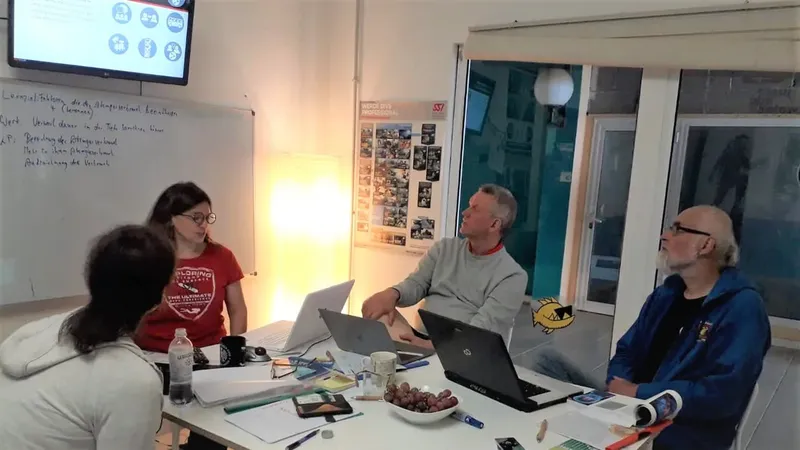 Quatre personnes sont assises autour d'une table avec des ordinateurs portables
